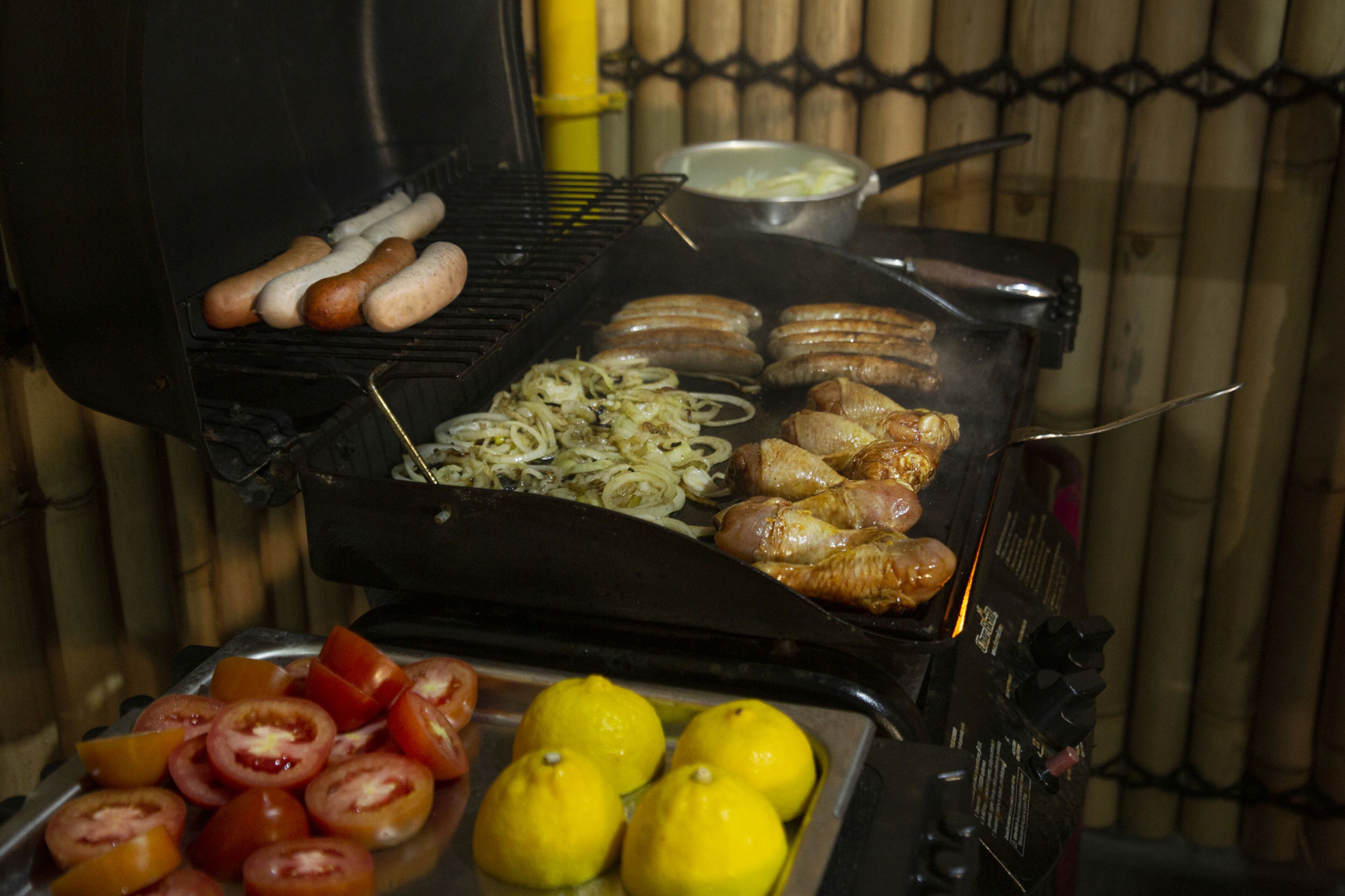 Ein Grill mit Würstchen, Hähnchen und Gemüse.