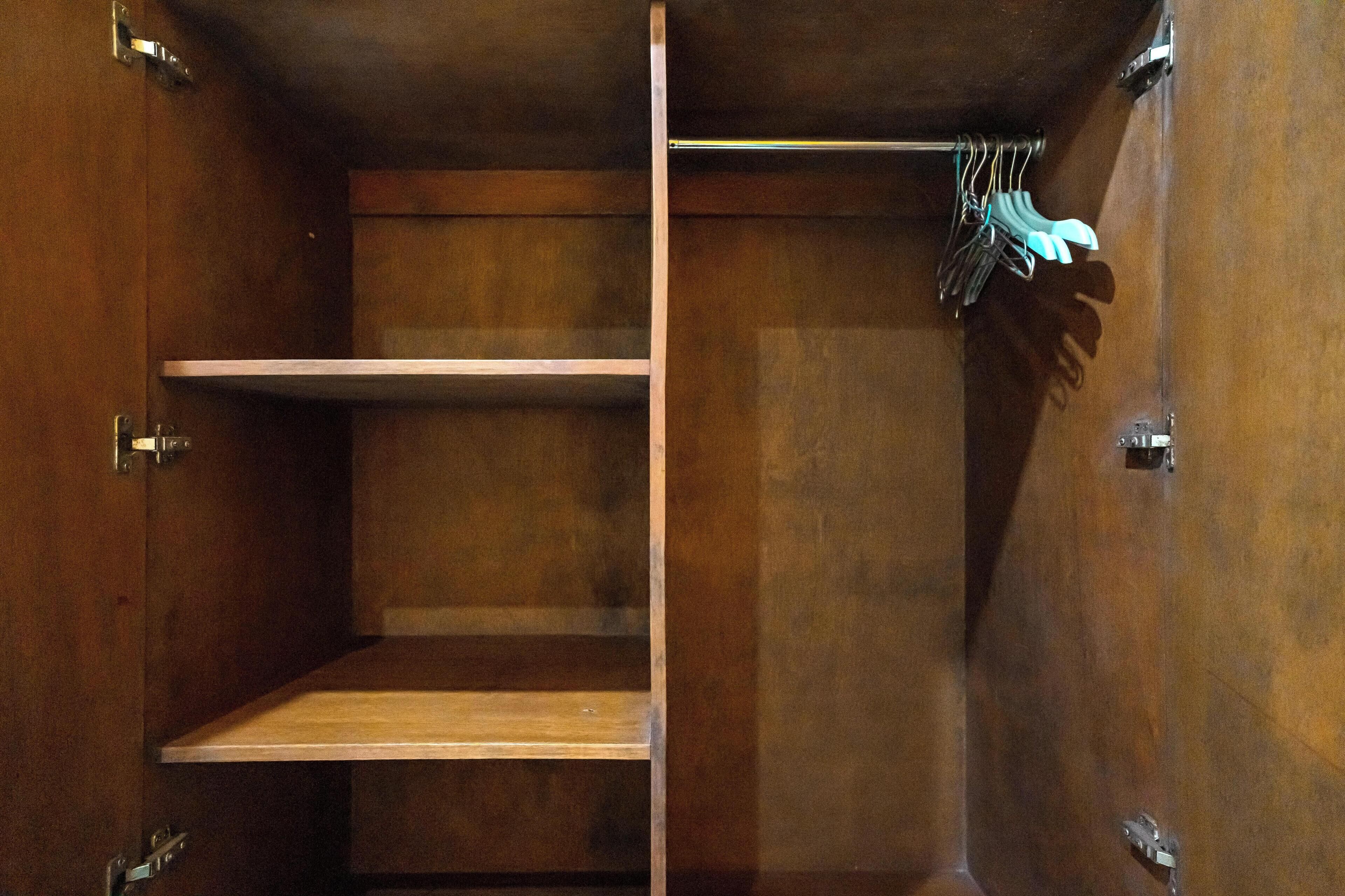 A wooden wardrobe with two shelves and a hanging rod.