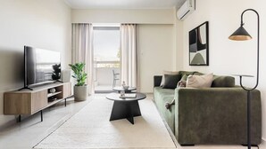 Un salon moderne avec un téléviseur à écran plat, un canapé vert, une table basse et un lampadaire.