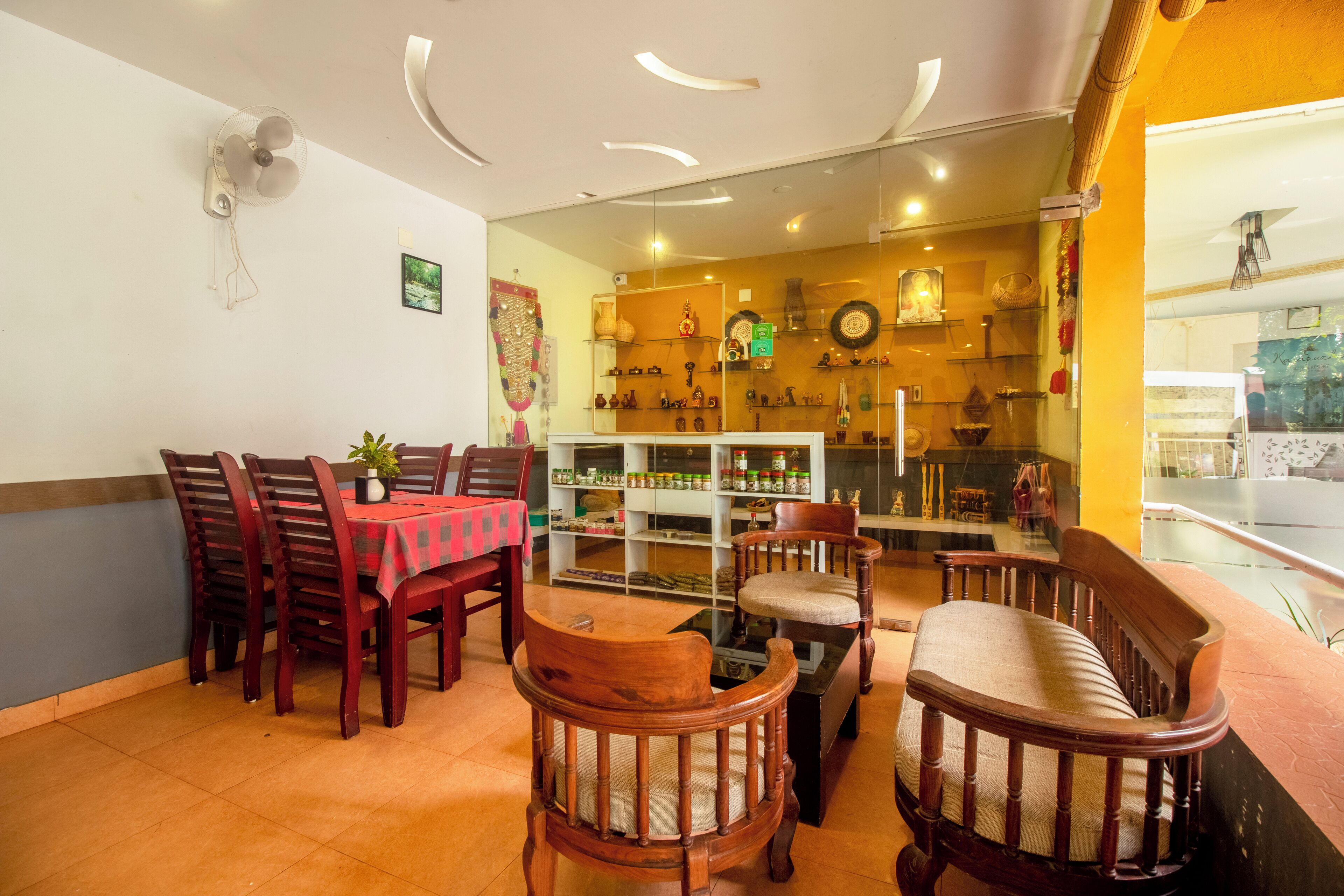 A dining area with wooden chairs and a table, a glass display case with various items, and a wall with shelves displaying decorative objects.