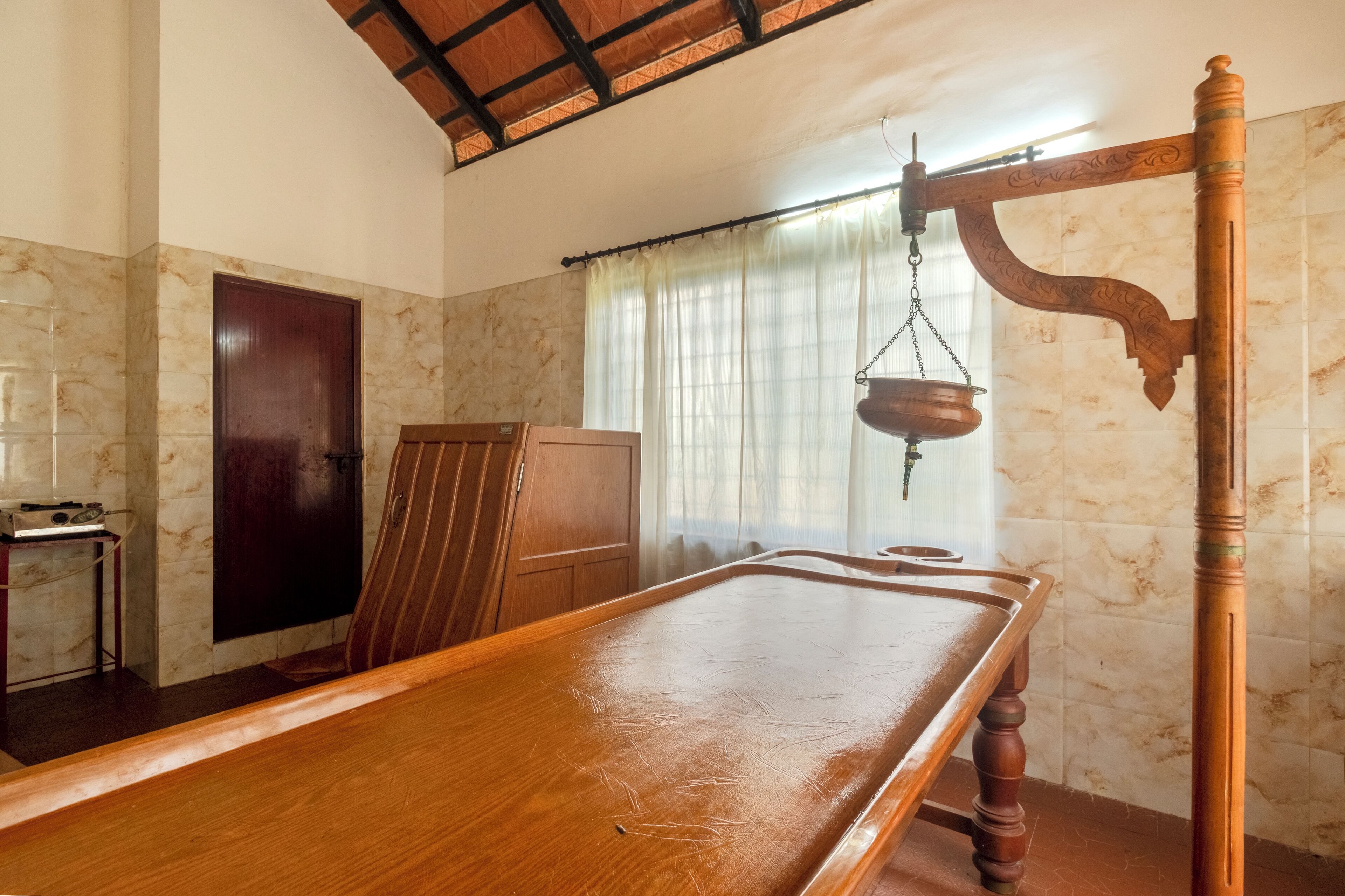 A room with a wooden table, a cabinet, and a hanging pot.