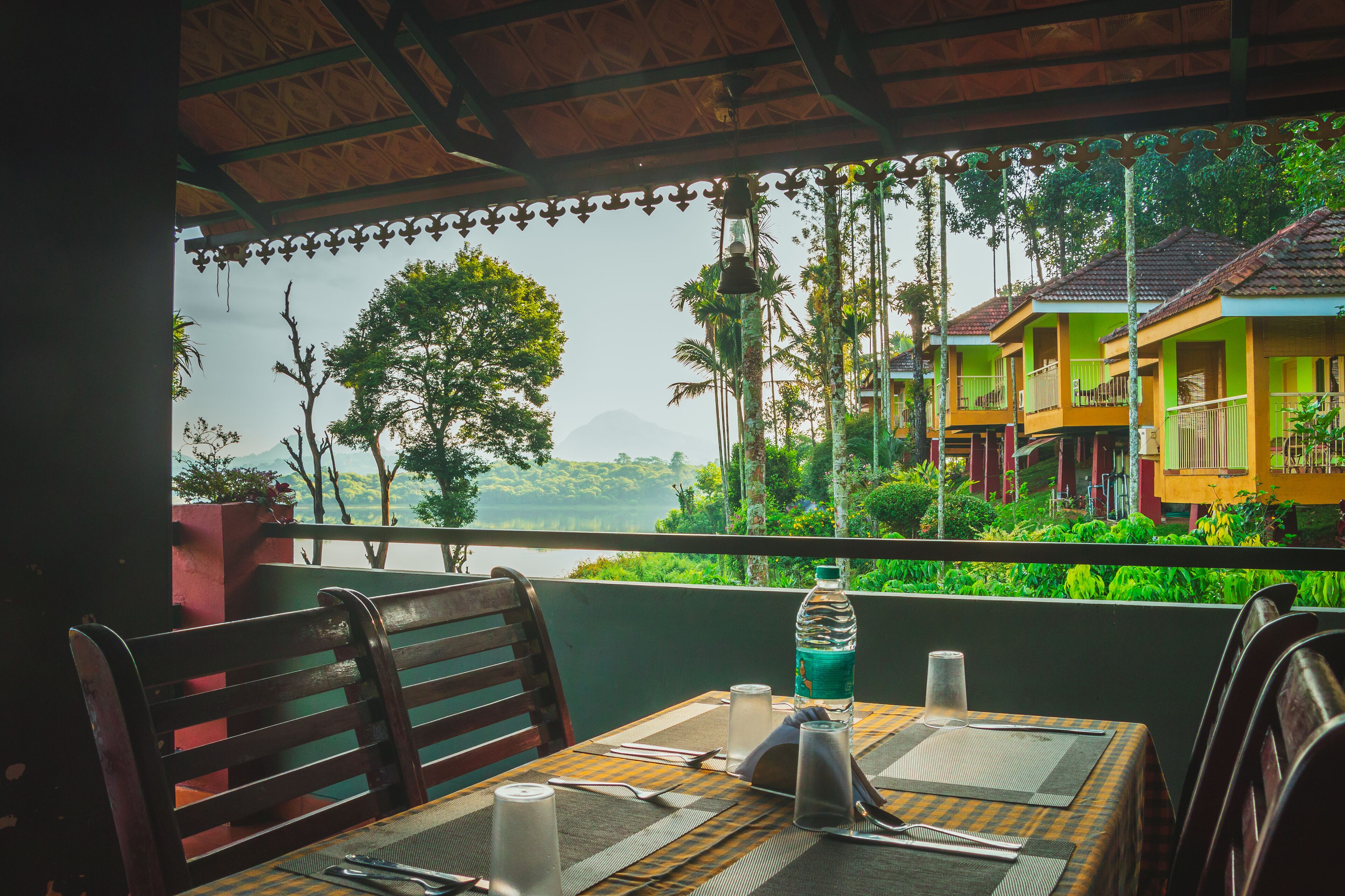 A table set for dining with a view of lush greenery and colorful buildings in the background.