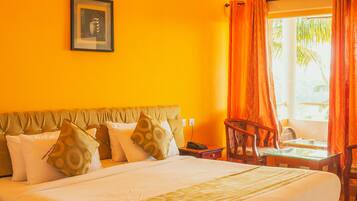 Habitación de hotel con una cama grande, un equipo de aire acondicionado, un ventilador de techo y una ventana con cortinas.