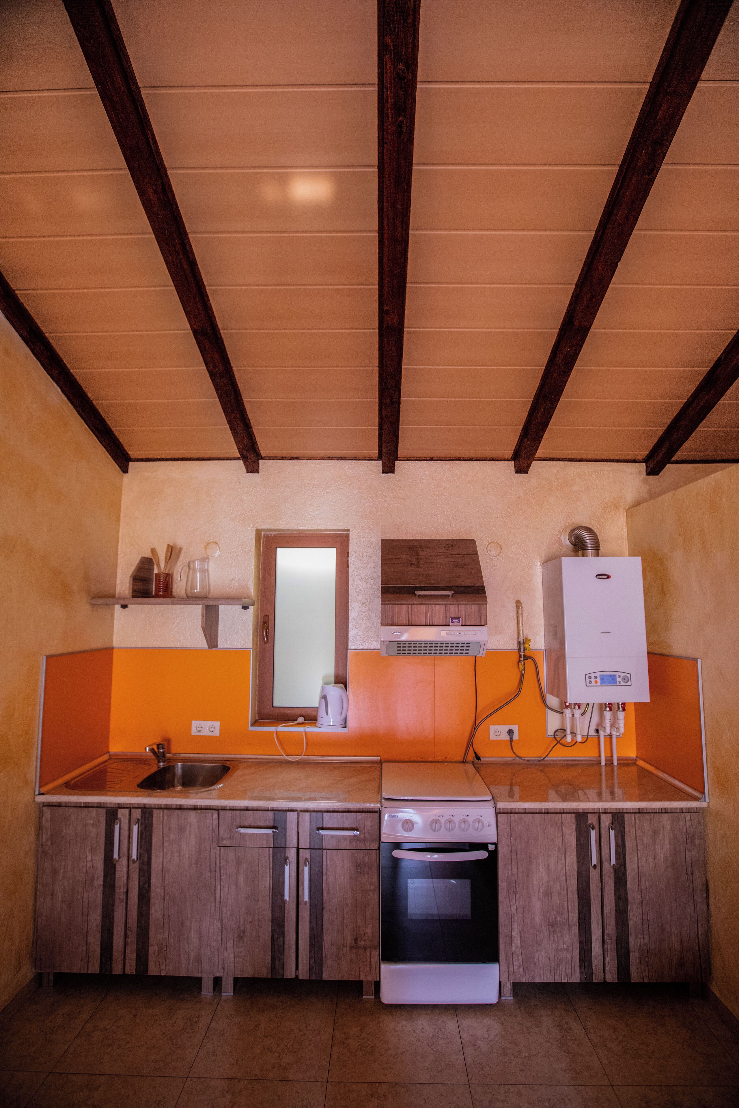 Una cocina con armarios de madera, estufa, fregadero y horno empotrado.
