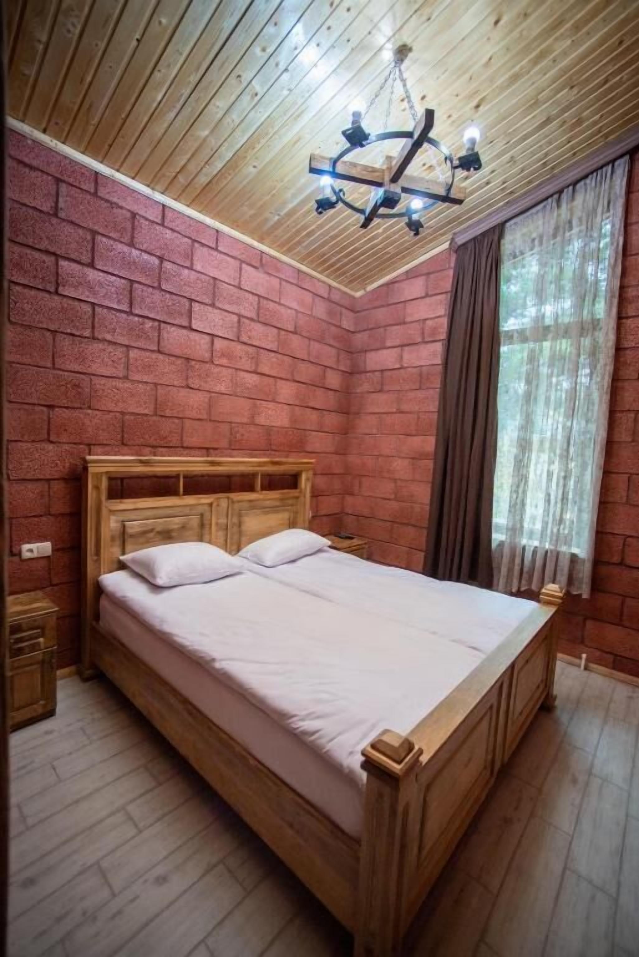 A wooden bed in a room with brick walls and a wooden ceiling.