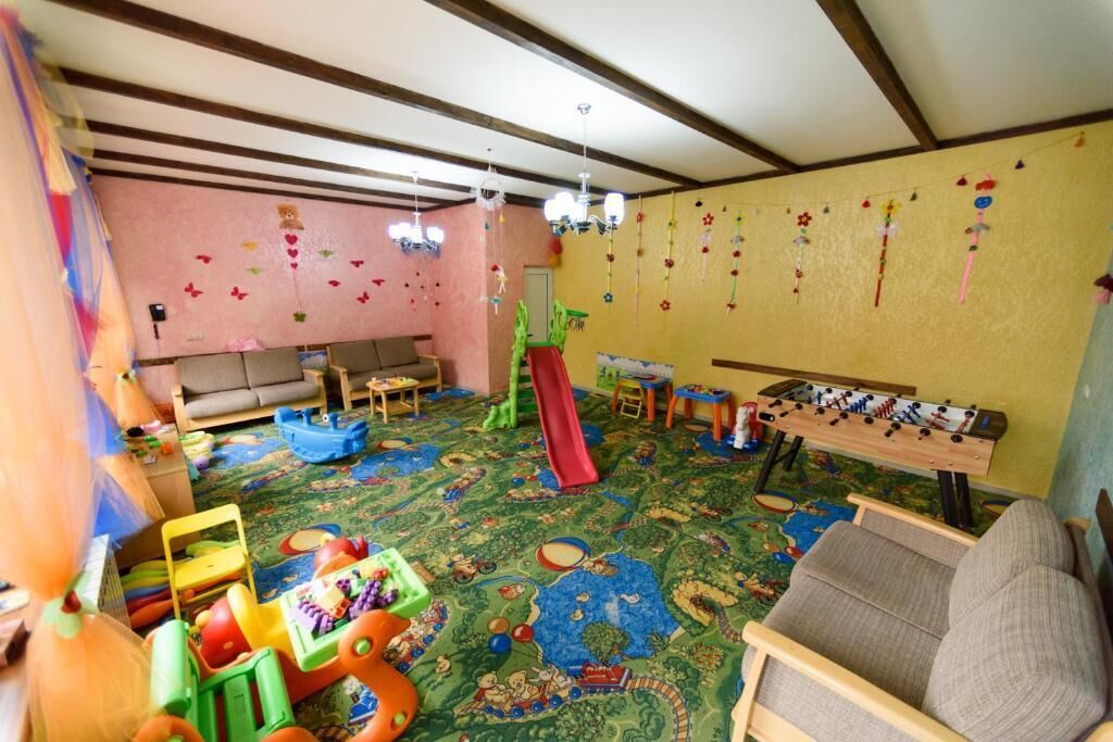 Ein Spielzimmer mit einem bunten Teppich, einer Rutsche und verschiedenen Spielsachen.