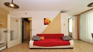 Una sala de estar moderna con un sofá rojo y blanco, un cuadro en la pared y piso de madera.