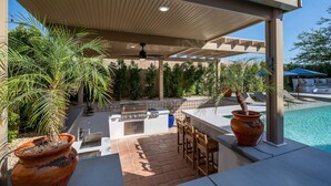 An outdoor patio with a grill, seating, and a pool. - Hacienda San Miguel | Resort Style Pool W/ Sunken Outdoor Kitchen (Indio)