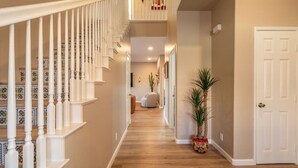 A hallway with a wooden floor, white railing, and a door at the end. - Hacienda San Miguel | Resort Style Pool W/ Sunken Outdoor Kitchen (Indio)
