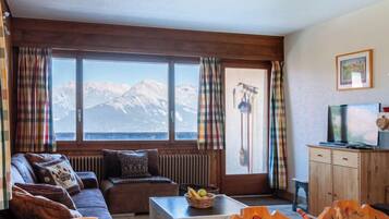 Un salon chaleureux avec un canapé, une table basse et une vue sur les montagnes grâce à de grandes fenêtres.