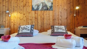 A wooden-paneled room with a bed, two pillows, a painting, and two bedside lamps. - Magrappé 344 by Interhome (Veysonnaz)