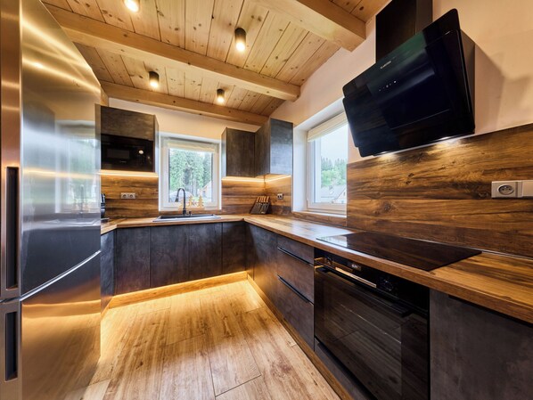 Una cocina moderna con techo de madera, electrodomésticos de acero inoxidable y un ventanal grande.