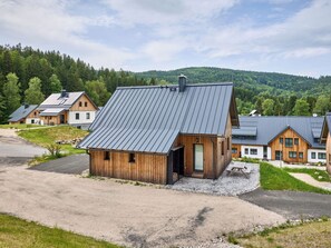 Un moderno rifugio con tetto spiovente, facciata in legno e vialetto in ghiaia.
