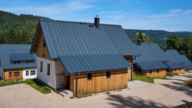 A modern lodge with a sloped roof, wooden cabins, and a scenic forest backdrop. - Vacation home Muhu by Interhome (Smržovka)
