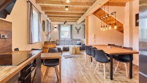 Una cucina moderna con travi in legno, un'area pranzo con tavolo e sedie in legno e un accogliente soggiorno con divano e camino.