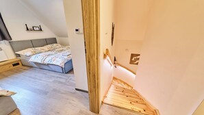 Una camera da letto con un letto, un comodino e una scala in legno che porta a un piano superiore.