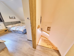 A bedroom with a bed, a bedside table, and a wooden staircase leading to an upper level. - Vacation home Muhu by Interhome (Smržovka)