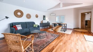 Ein modernes Wohnzimmer mit einer Couch, Sesseln, einem Couchtisch und einem Teppich.