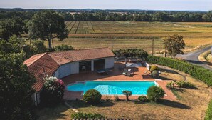 Ein Haus mit Schwimmbad, Terrasse und Blick ins Grüne.