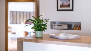 Eine Küchenarbeitsplatte mit einem Blumentopf, einer weißen Ablage und einem gerahmten Bild an der Wand.