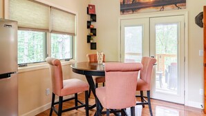 A dining area with a round table and four pink chairs, a refrigerator, and two windows with blinds. - Spring in Mtns Poplar Treehouse Near Asheville - Pet Friendly (Marshall)