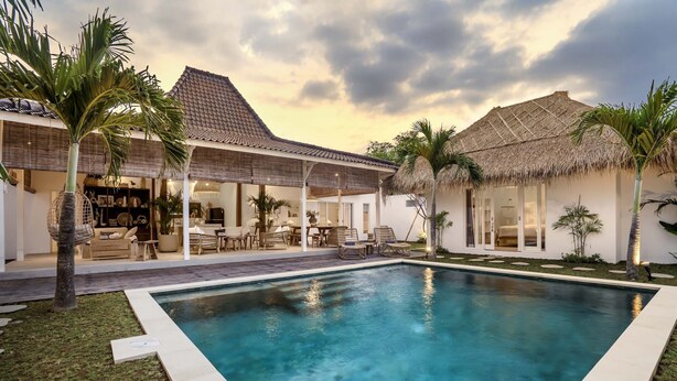 A poolside area with a clear pool, lounge chairs, and a covered seating area. - A Casa Di Renucci by Alfred in Bali (Seminyak)