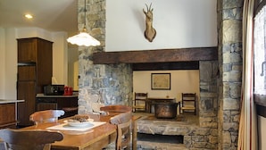 A dining area with a stone fireplace, wooden furniture, and a mounted animal head. - Apartamentos Linsoles (Benasque)