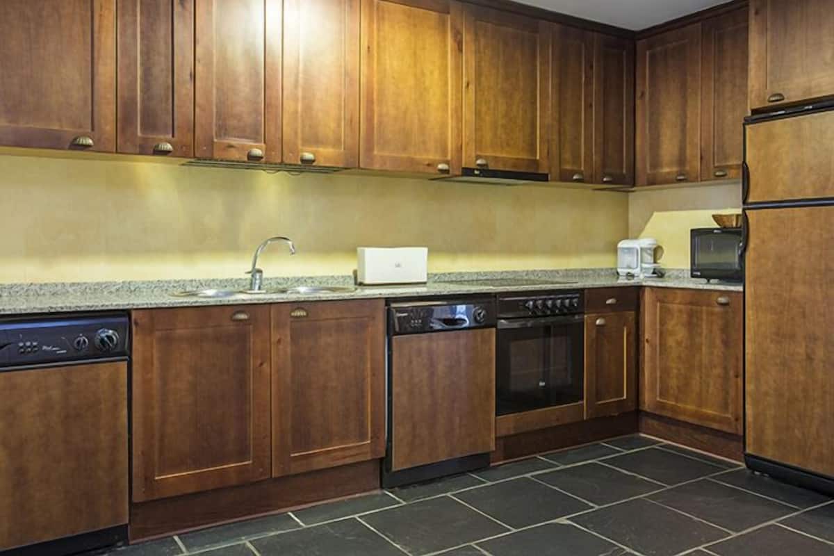 Una cocina con armarios de madera, lavavajillas, estufa y microondas.
