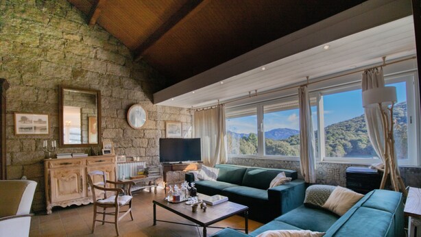 A cozy living room with a stone wall, a green sofa, a wooden coffee table, and a television. - Holiday Home 'Chez Jean Viti' with Private Garden and Wi-Fi (Levie)
