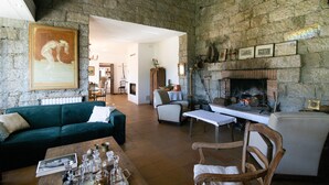 A rustic interior with a stone wall, a fireplace, a green sofa, and a wooden table. - Holiday Home 'Chez Jean Viti' with Private Garden and Wi-Fi (Levie)