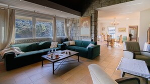 A spacious living area with a green sofa set, a coffee table, and a dining area with chairs and a table. - Holiday Home 'Chez Jean Viti' with Private Garden and Wi-Fi (Levie)
