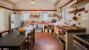 A kitchen with a dining table, chairs, a refrigerator, and various kitchen appliances. - Holiday Home 'Chez Jean Viti' with Private Garden and Wi-Fi (Levie)