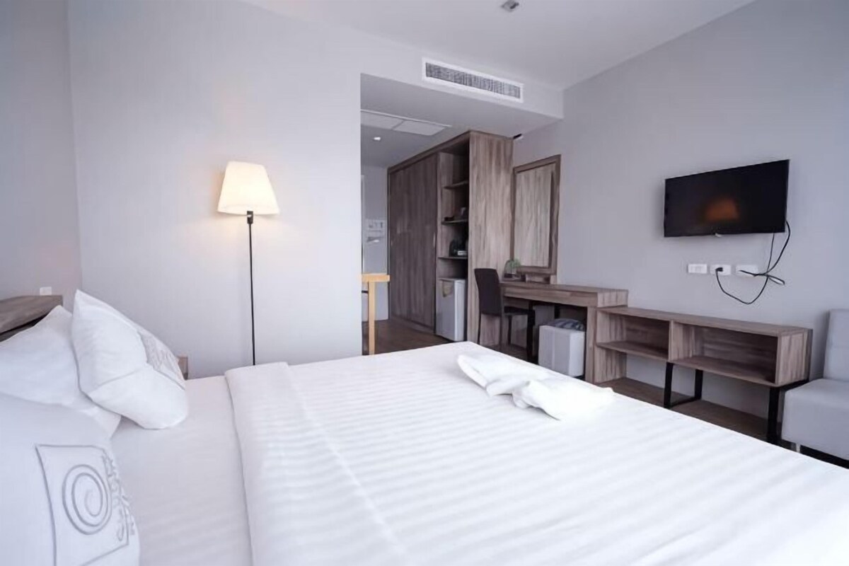 Hotellihuone, jossa on sänky, työpöytä, televisio ja lamppu.