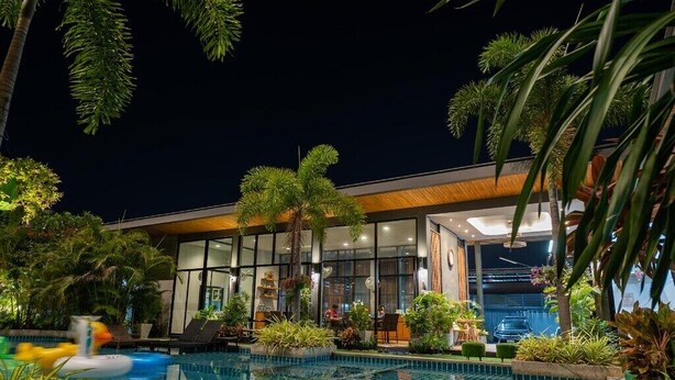 Un hôtel moderne doté d’une piscine, entouré d’une végétation luxuriante et de palmiers.