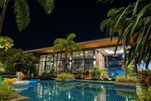 Ein modernes Hotel mit Schwimmbad, umgeben von üppiger Vegetation und Palmen.