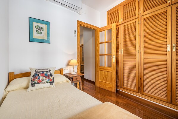 A bedroom with a bed, bedside table, lamp, and a wooden wardrobe.