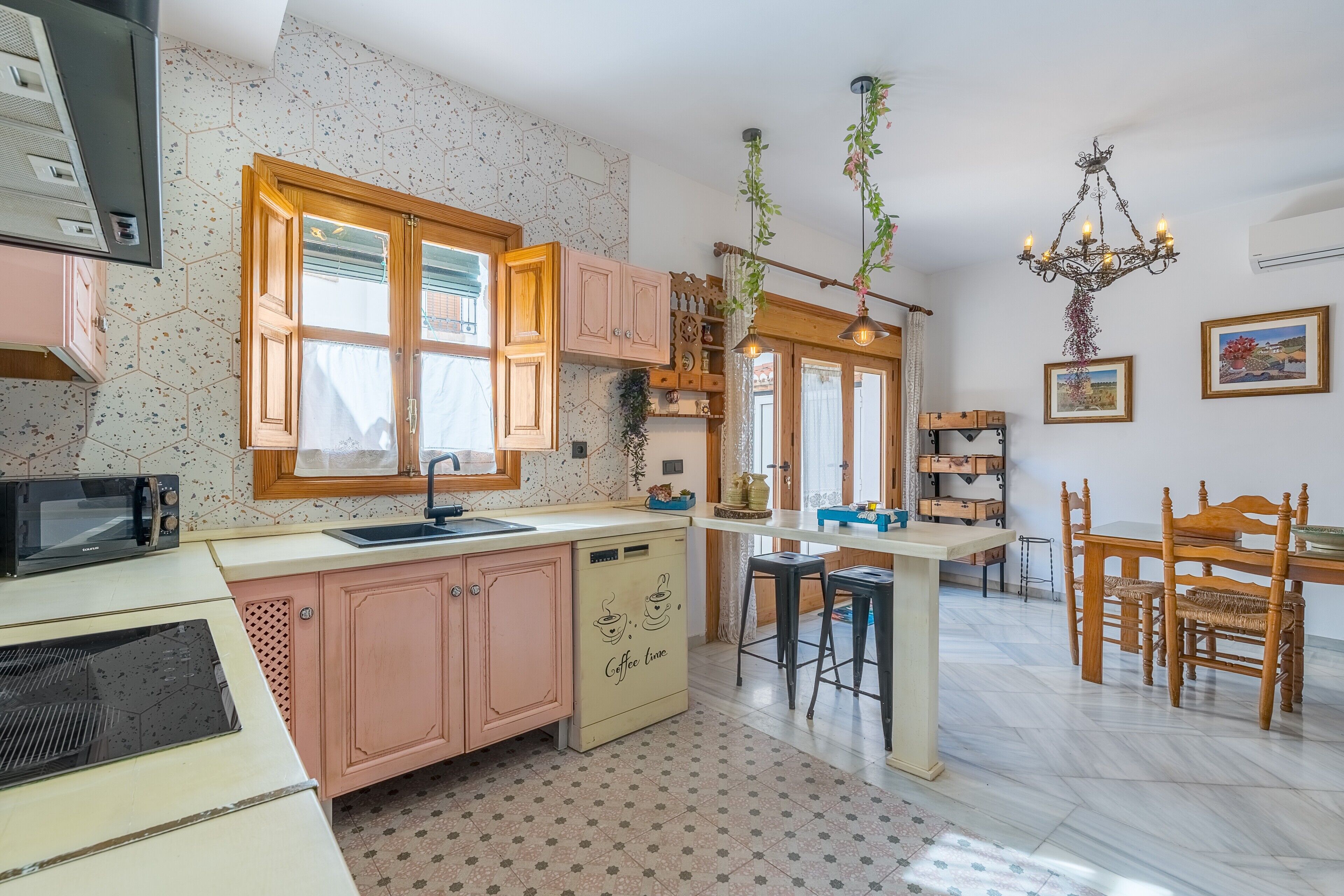 Una cocina con armarios de madera, microondas, cafetera y comedor con mesa y sillas.