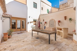 A courtyard with a table, potted plants, and a door.