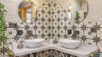 Een badkamer met twee wasbakken, tegels met sterrenpatroon, en twee ronde spiegels.