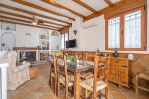 A spacious living area with a fireplace, wooden furniture, a TV, and a large window. - Vacation Home "El Valle Verde" with Mountain View, Private Terrace & Wi-Fi (Lecrin)