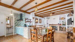 A spacious kitchen with wooden beams, a tiled backsplash, and a dining area with a glass table and wooden chairs. - Vacation Home "El Valle Verde" with Mountain View, Private Terrace & Wi-Fi (Lecrin)