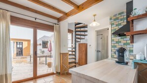 A kitchen with a wooden countertop, a spiral staircase, and a view of the outside. - Vacation Home "El Valle Verde" with Mountain View, Private Terrace & Wi-Fi (Lecrin)