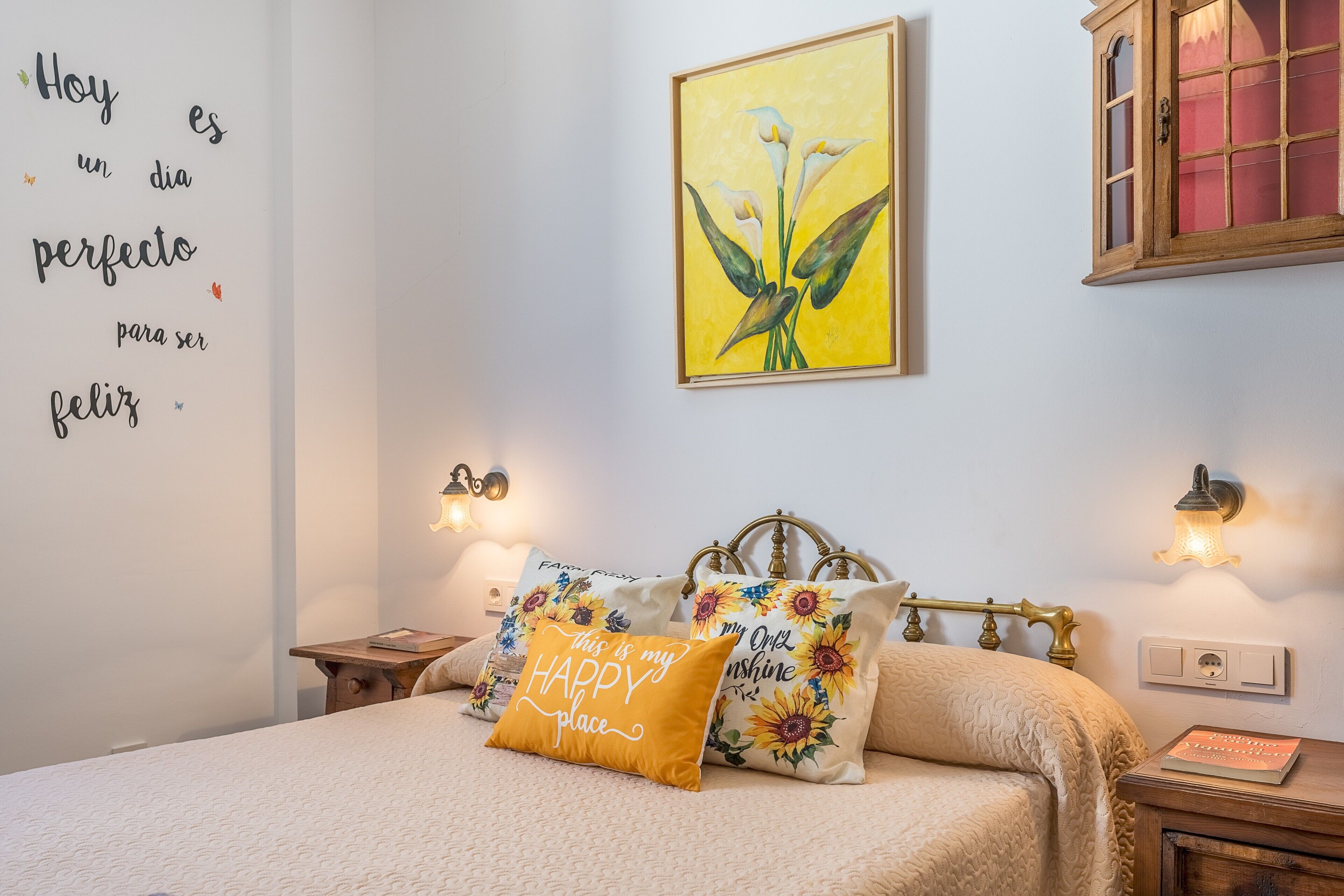 A bedroom with a bed, decorative pillows, a wall art piece, and bedside lamps.