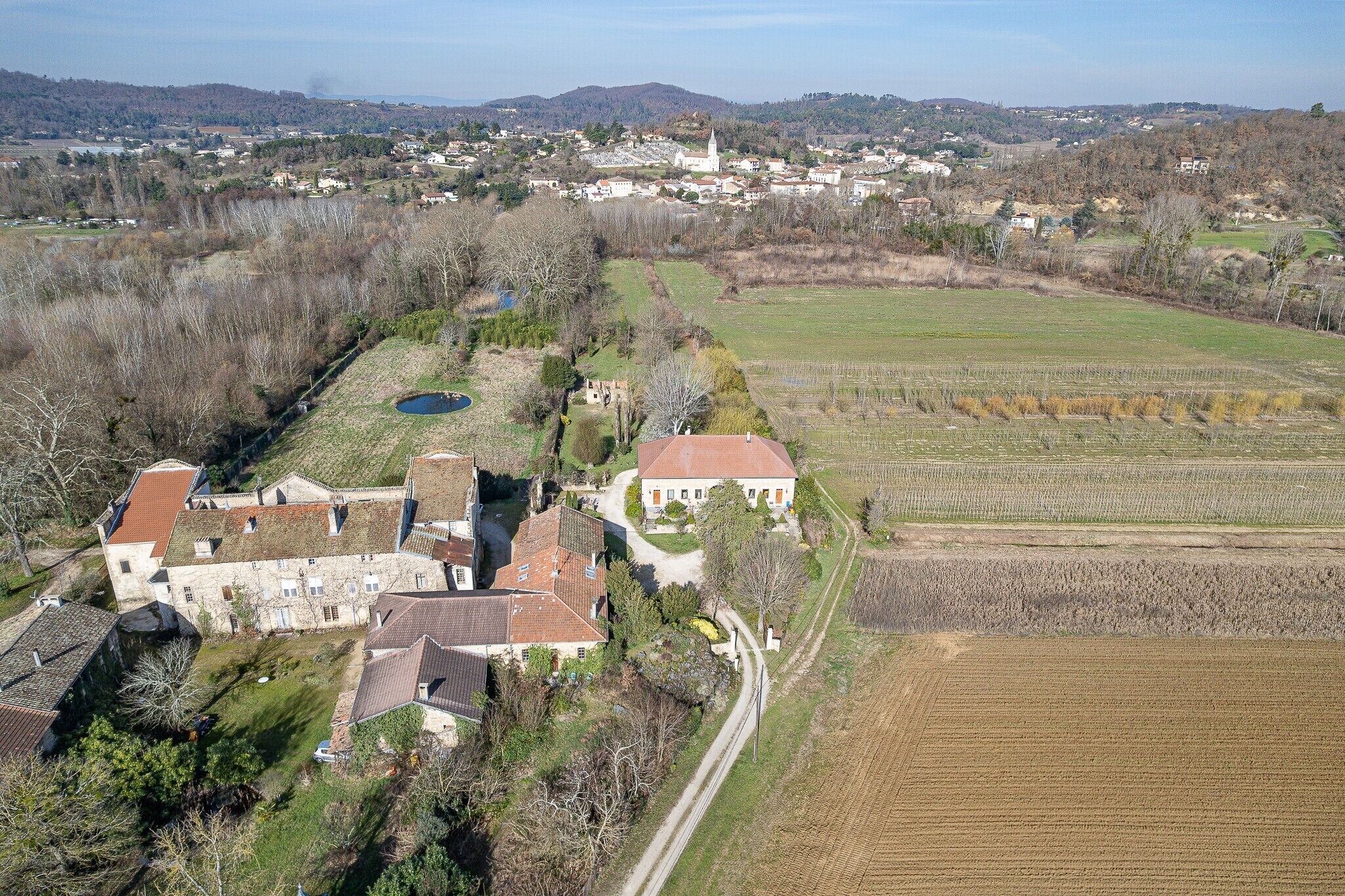 Una vista aerea di un villaggio rurale con edifici in pietra, una chiesa e campi circostanti.