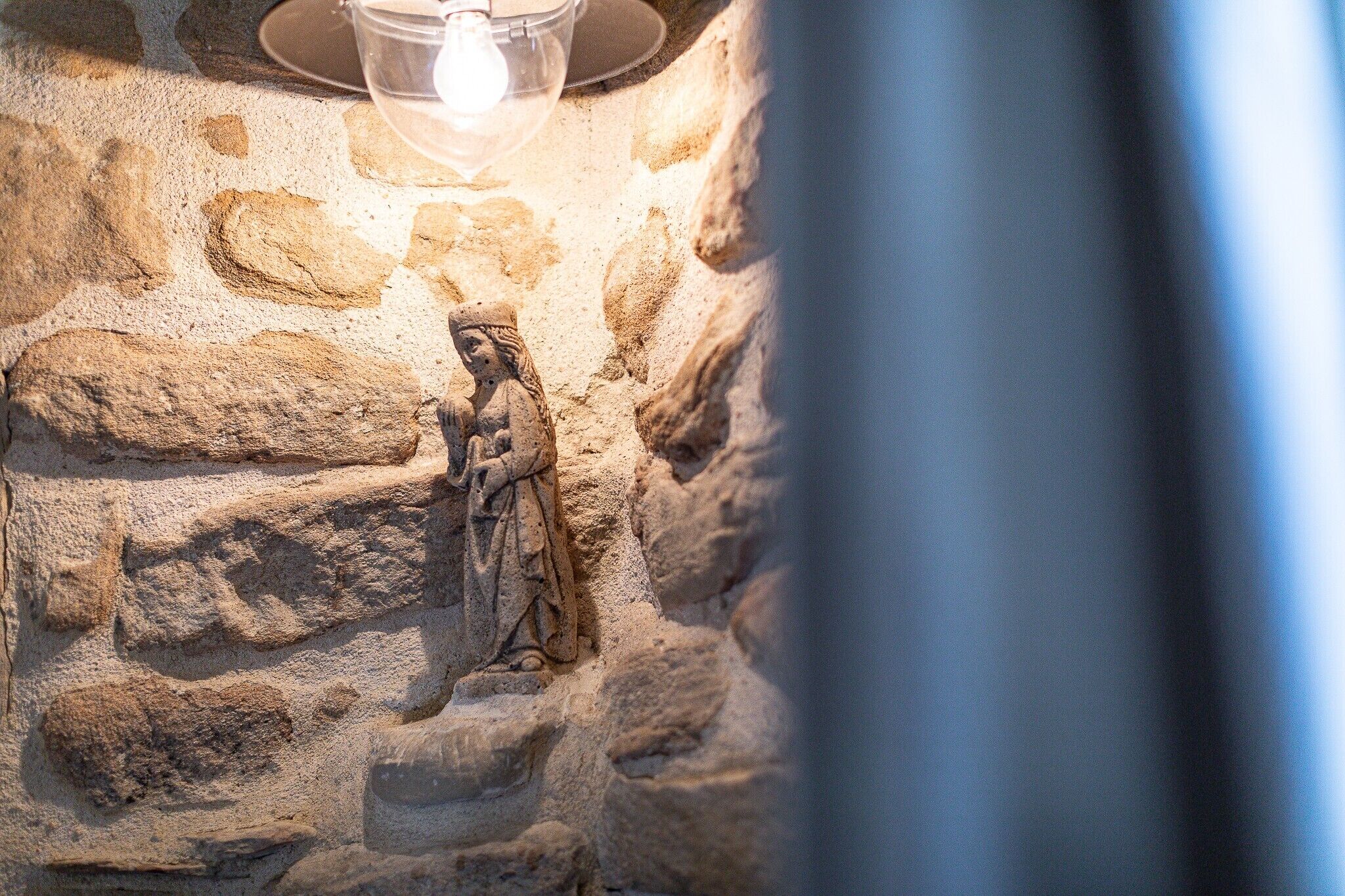 Een stenen muur met een klein beeldje en een lamp.