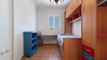 A bedroom with a bed, wardrobe, shelves, and a window.