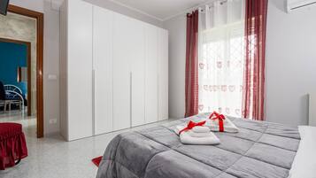 Een slaapkamer met een bed, een kledingkast, een rode stoel en uitzicht op een blauwe kamer.
