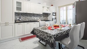 Eine moderne Küche mit weißen Schränken, einer Steinrückwand und einem Essbereich mit Tisch für zwei Personen.