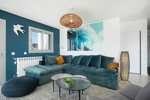 Uma sala de estar moderna com sofá modular, uma mesa de centro redonda de vidro e uma grande pintura abstrata.