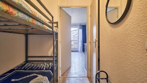A dormitory room with bunk beds, a mirror, and a door leading to a balcony. - Studio 'Les 2 Alpes' with Mountain View and Balcony (Les Deux Alpes)